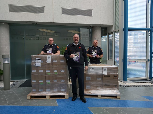 Markham Fire and Emergency Services Fire Chief Adam Grant standing in front of the 474 combination smoke and carbon monoxide alarms received through Safe Community Project Zero. Behind him are Deputy Fire Chief Matt Keay (L) and Deputy Fire Chief Chris Nearing (R).